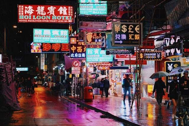 A street in China at night, neon signs shining on the pavement in Mandarin.