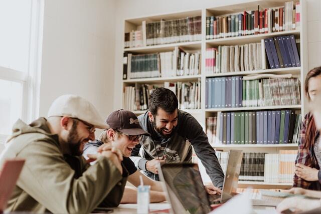 Three young professionals laugh together as they work in a office.