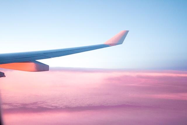 An image of a plane wing against a pink and blue sky.