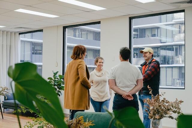 Four professionals stand in an office and char together, smiling.