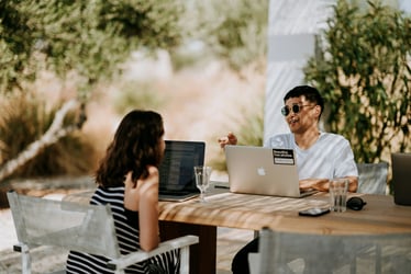 Man and woman working remotely together from an outdoors location