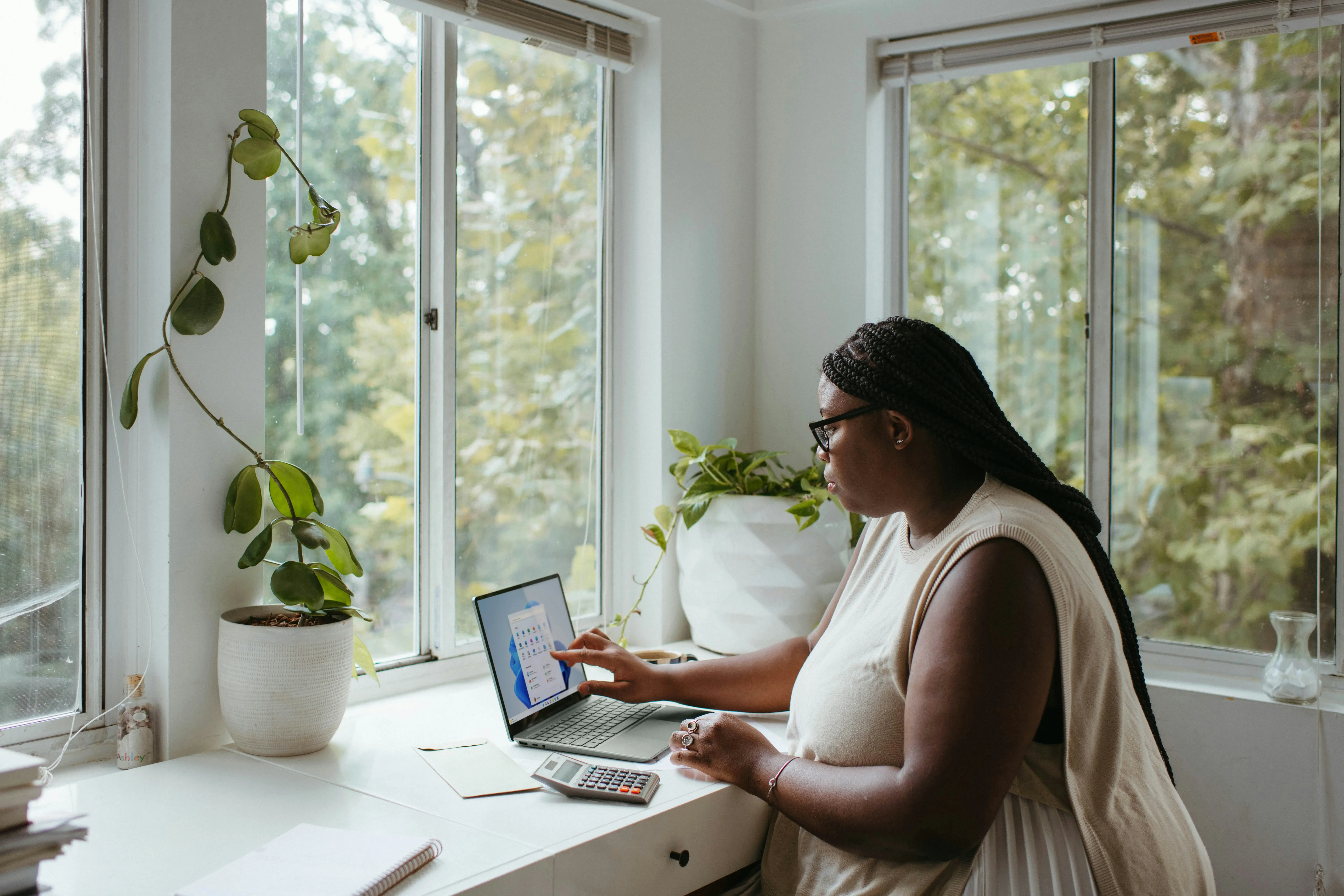 Woman working remotely on her desk with a foliage view